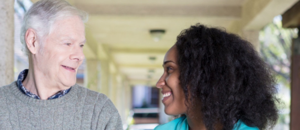 A caregiver and a senior man talking on a porch