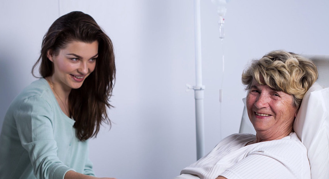 A caregiver helping a senior woman with an activity at the table
