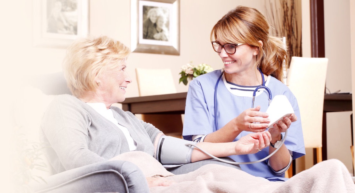 A nurse checking a senior woman's blood pressure at home