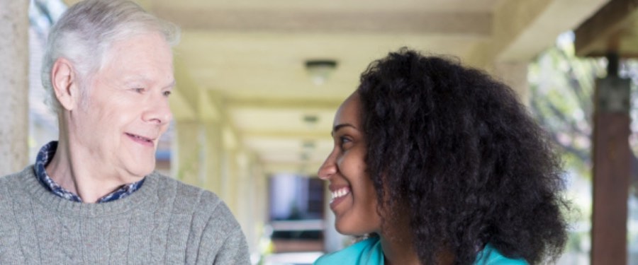 A caregiver and a senior man talking on a porch