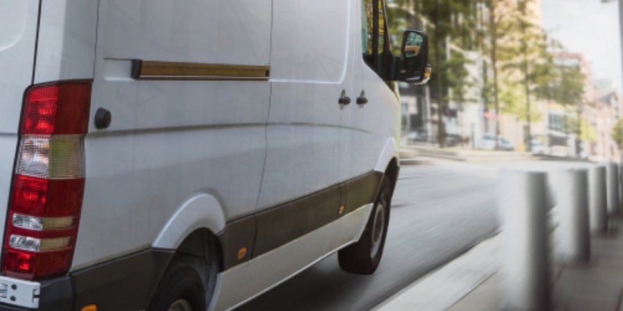 A white van driving along a city street