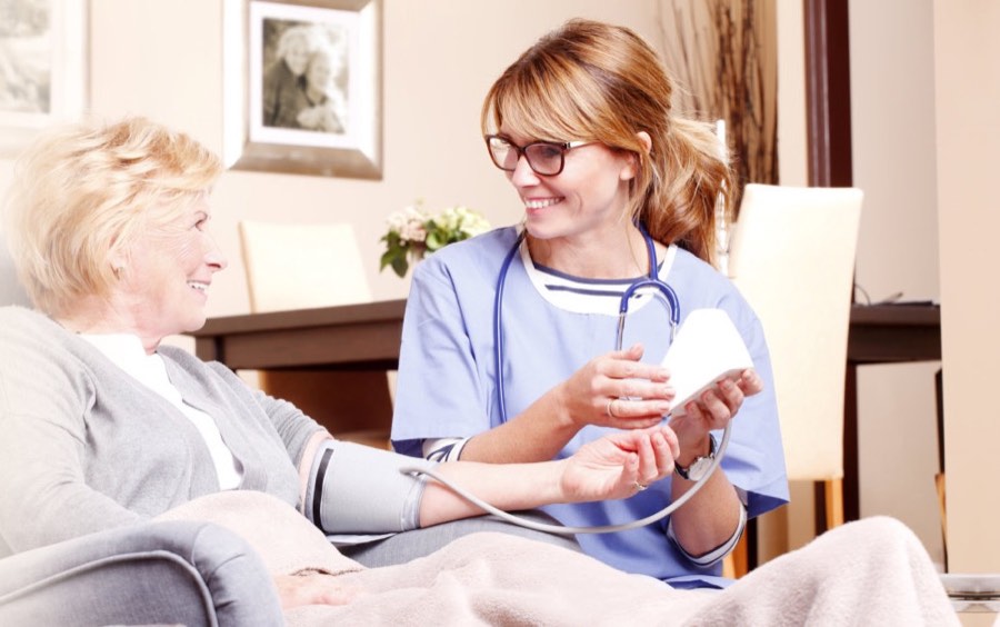 A nurse checking a senior woman's blood pressure at home