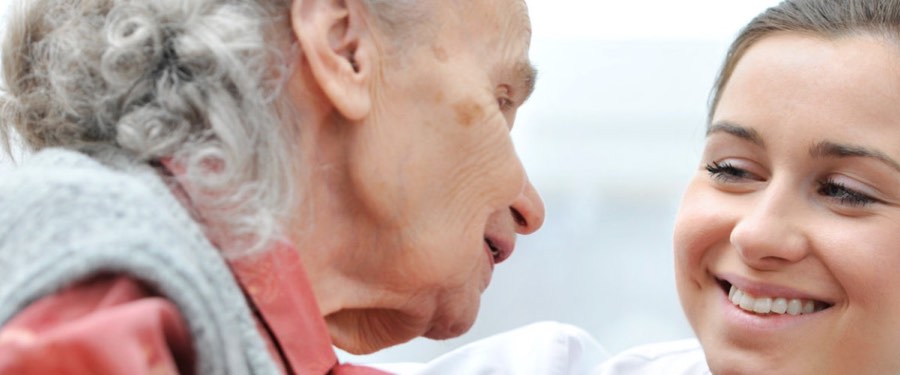 A young caregiver leaning close to a senior woman