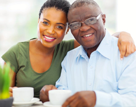 A young caregiver with her arm around a smiling senior man