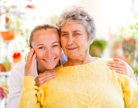 A caregiver hugging a senior woman in a garden